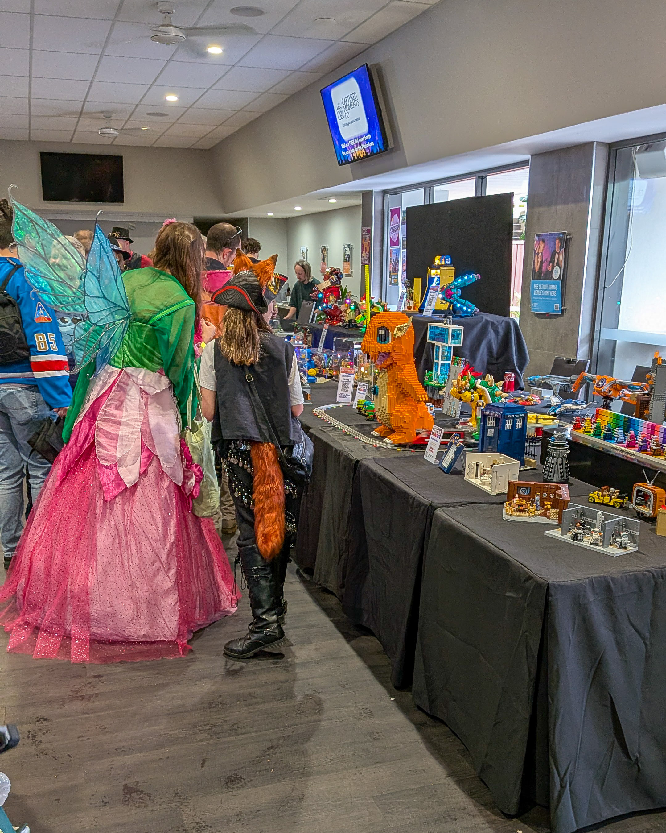 Cosplayers dressed as a fairy and a pirate admiring the Rainbow Bricks LEGO display