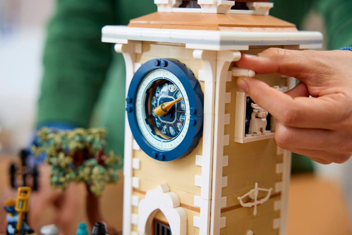 A hand turning the knob on the side of the clock tower