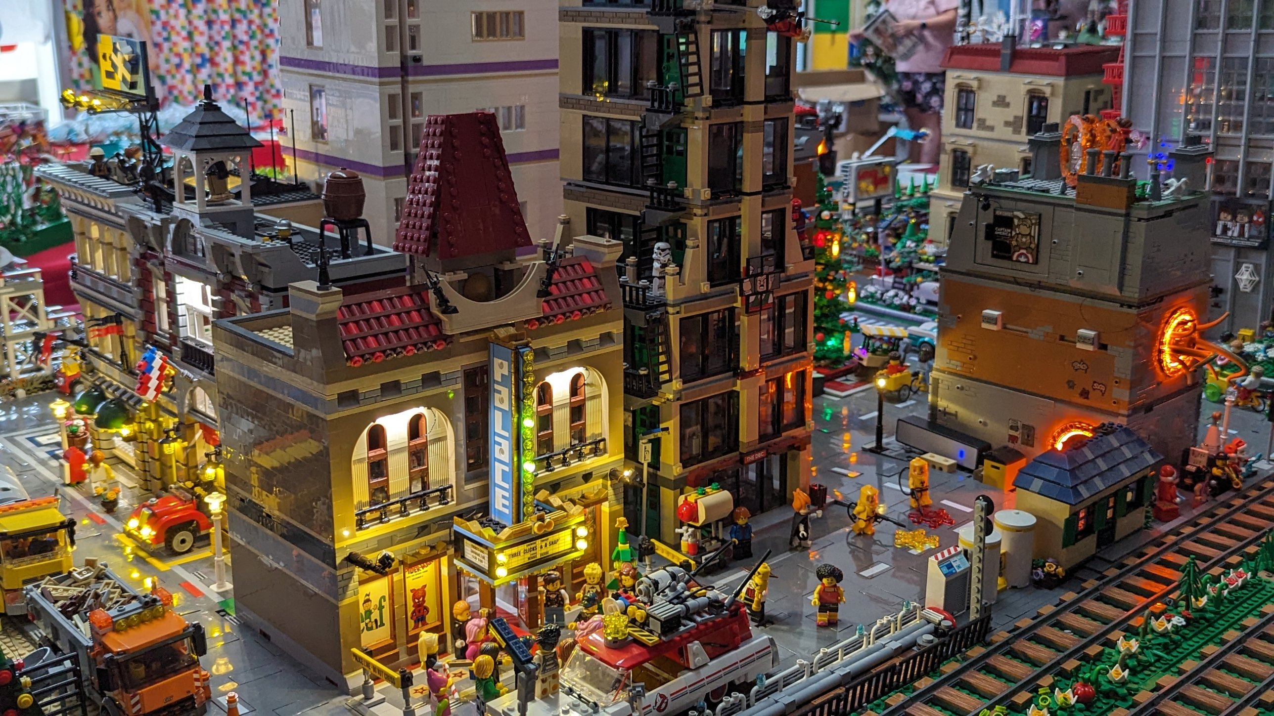 A lit LEGO city street with the Palace Cinema, a tall apartment building, minifigures and vehicles